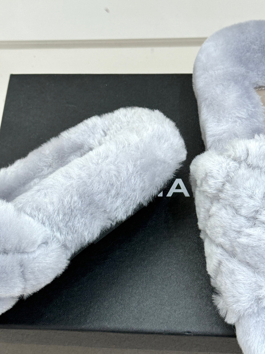 Light blue plush slide sandals showing curved toe strap and soft textured surface