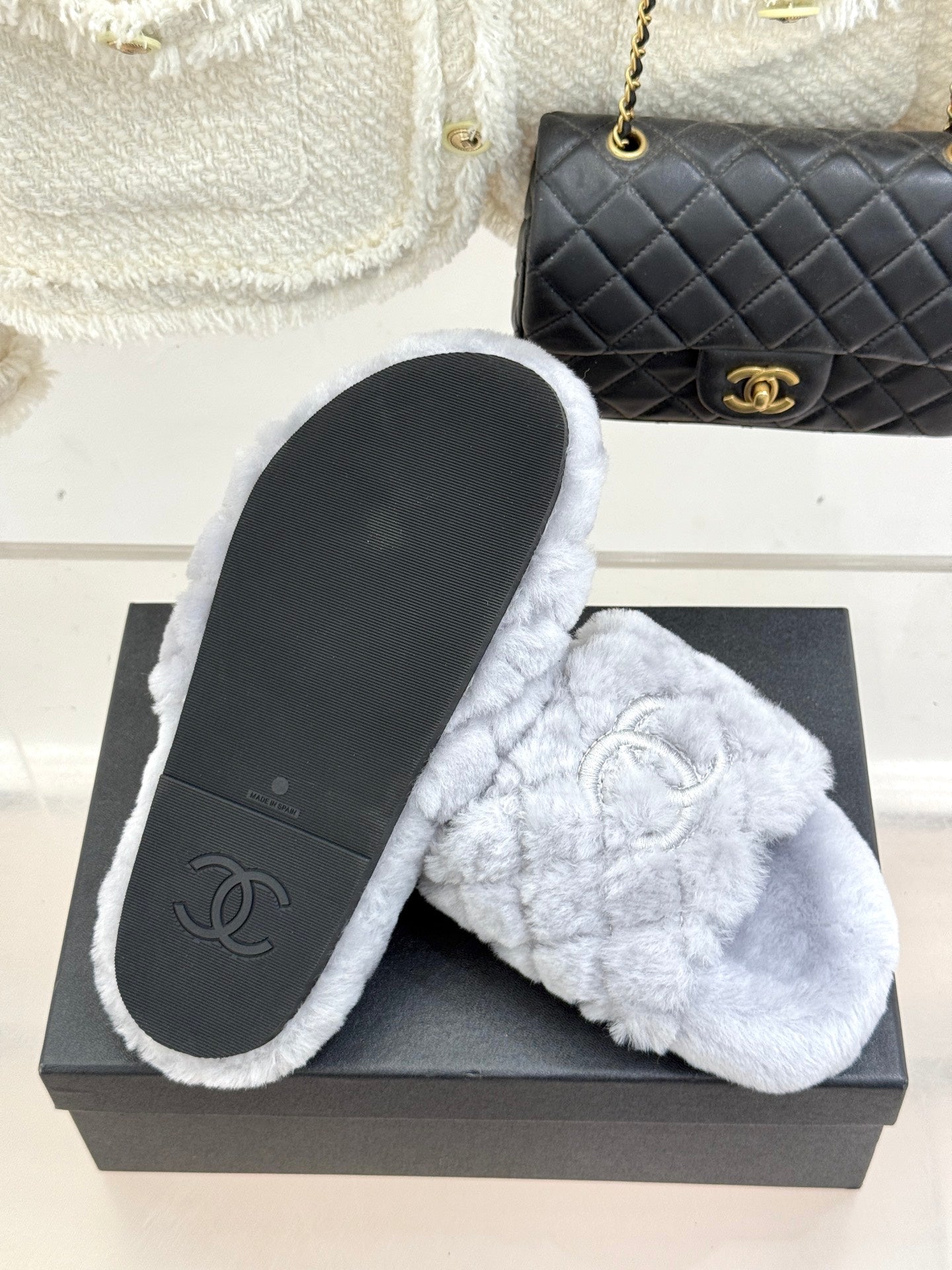 Light blue plush slide sandals with logo emblem and black outsole underside