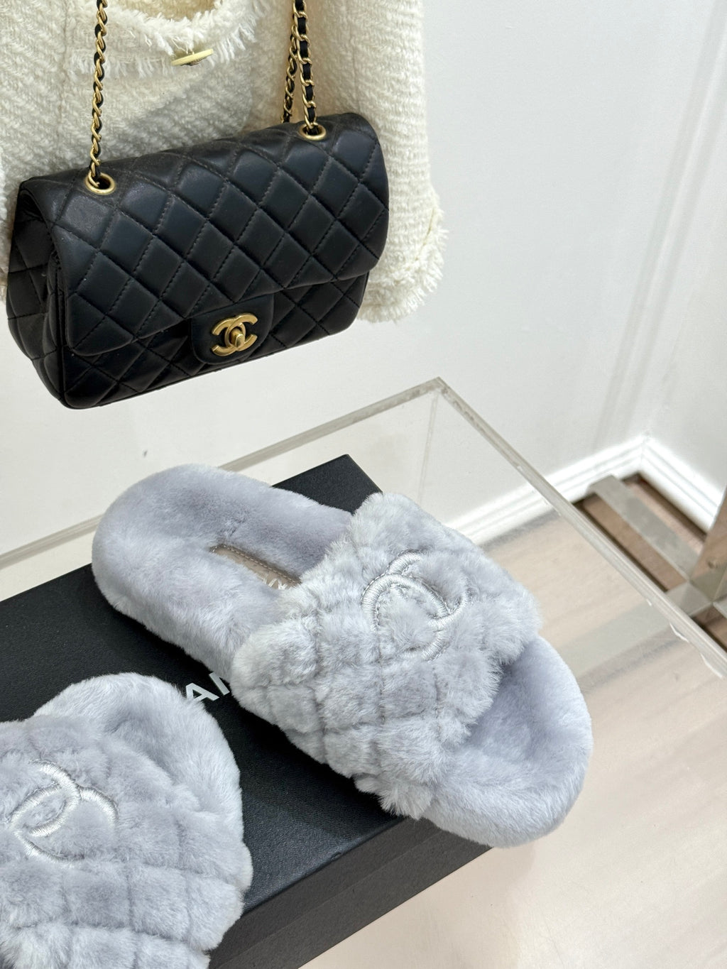 Light blue plush slide sandals on a black box, with logo emblem on front