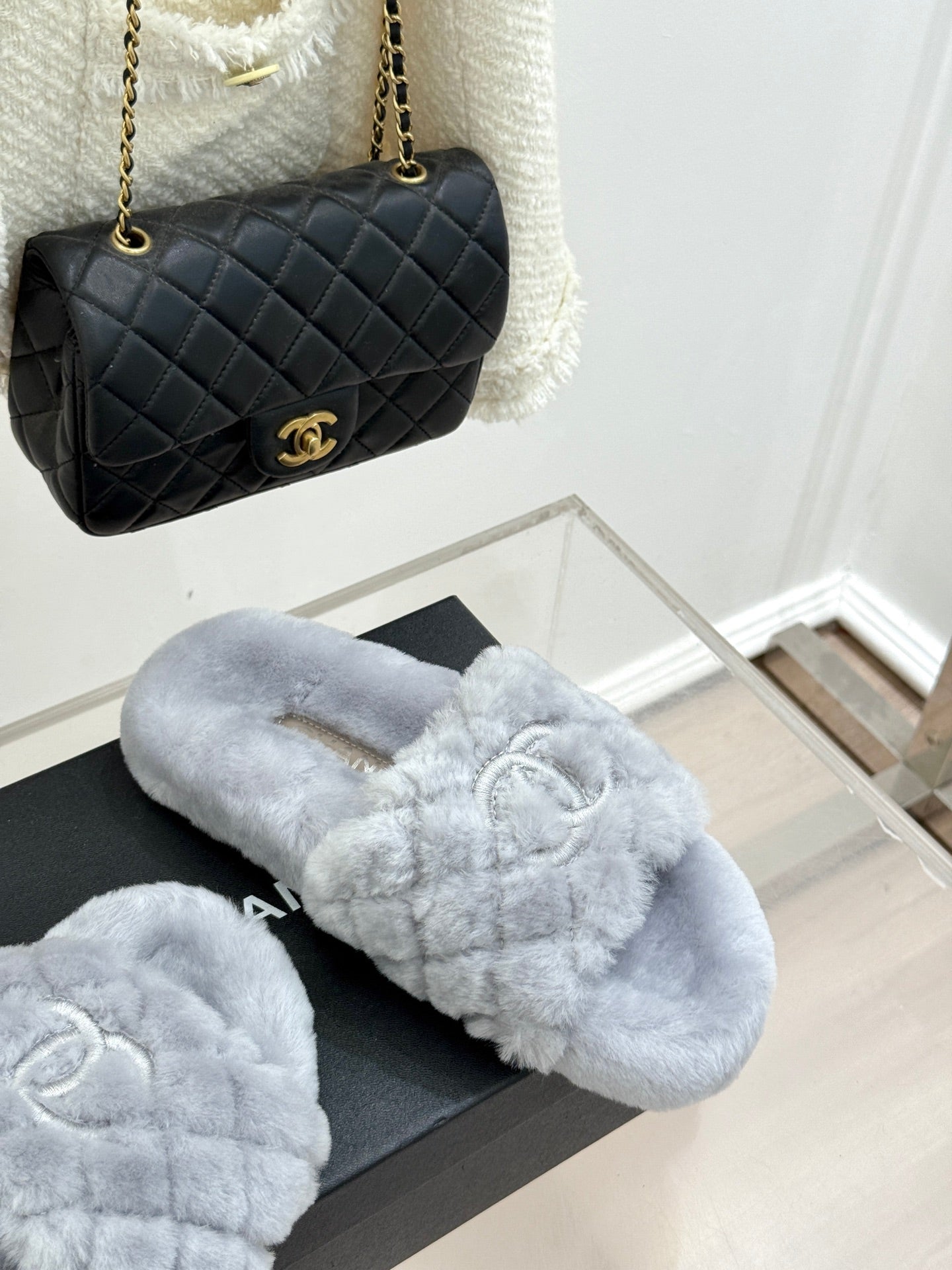 Light blue plush slide sandals on a black box, with logo emblem on front
