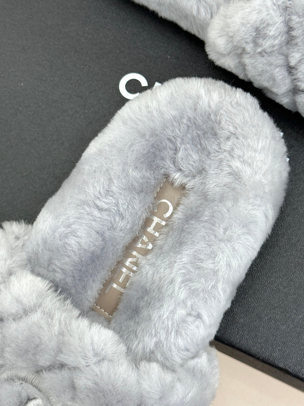 Light blue plush slide sandals showing gold logo label inside the strap