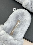 Light blue plush slide sandals showing gold logo label inside the strap