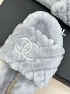 Light blue plush slide sandals with large logo emblem on the front strap
