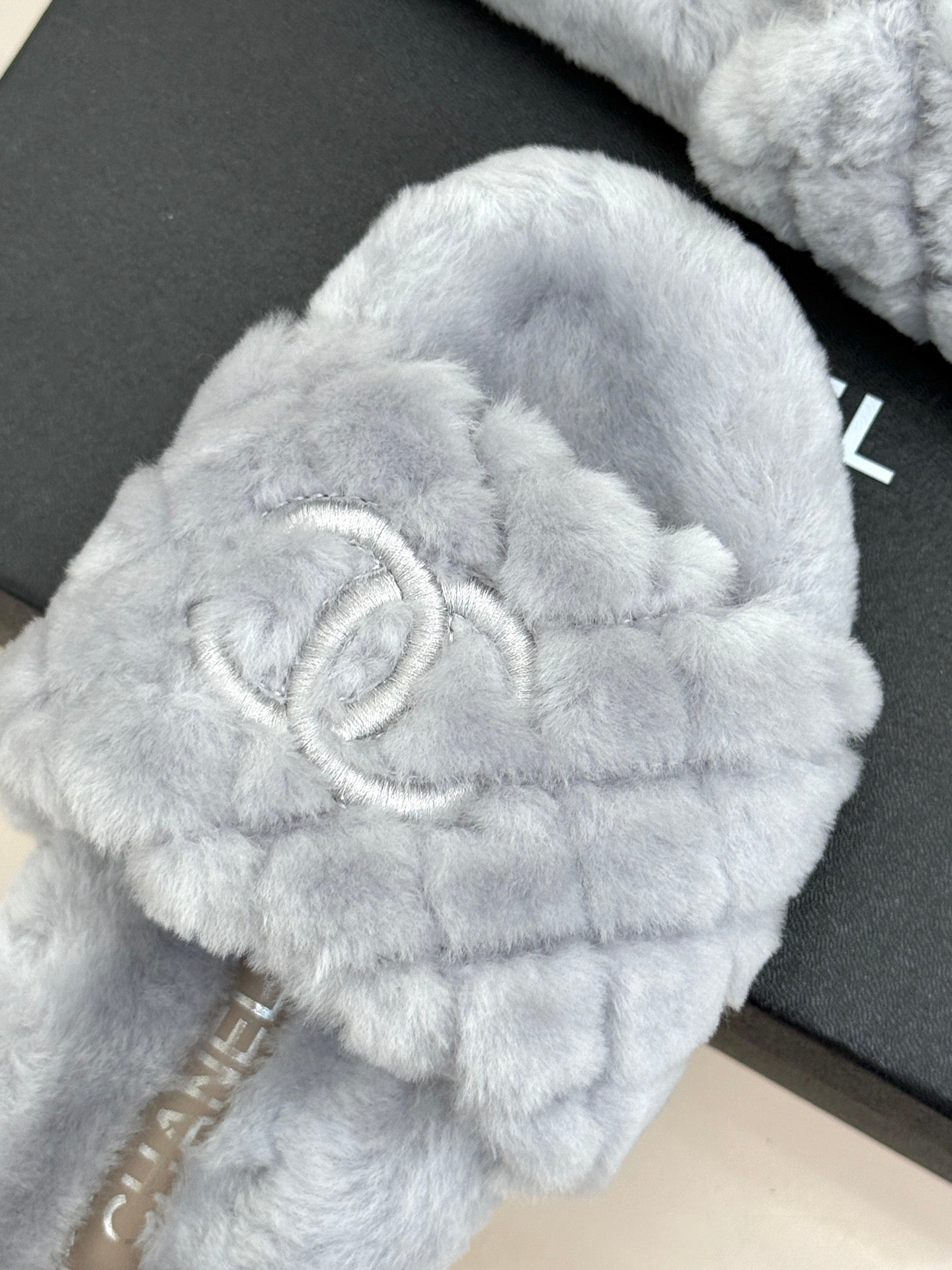 Light blue plush slide sandals with large logo emblem on the front strap