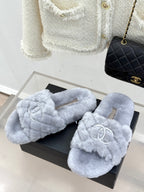 Light blue plush slide sandals with bow-like front and interlocking logo emblem