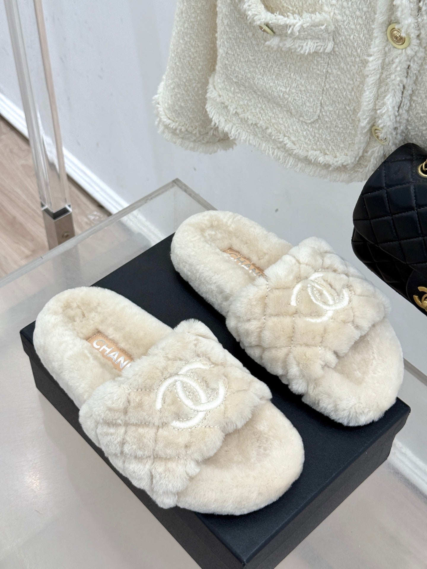 Pair of cream plush slide sandals with embroidered double-C logos on black box