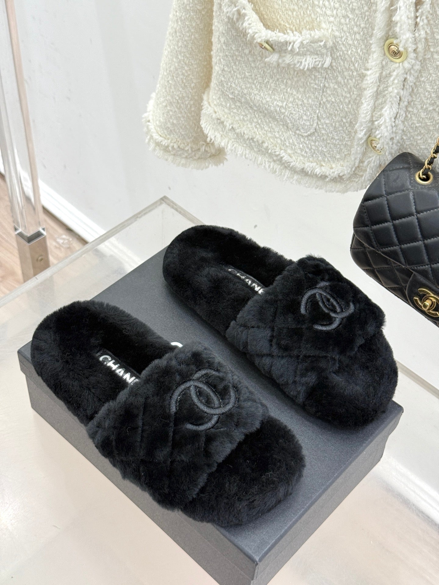 Dark faux-fur Chanel slides, front view on gray display box