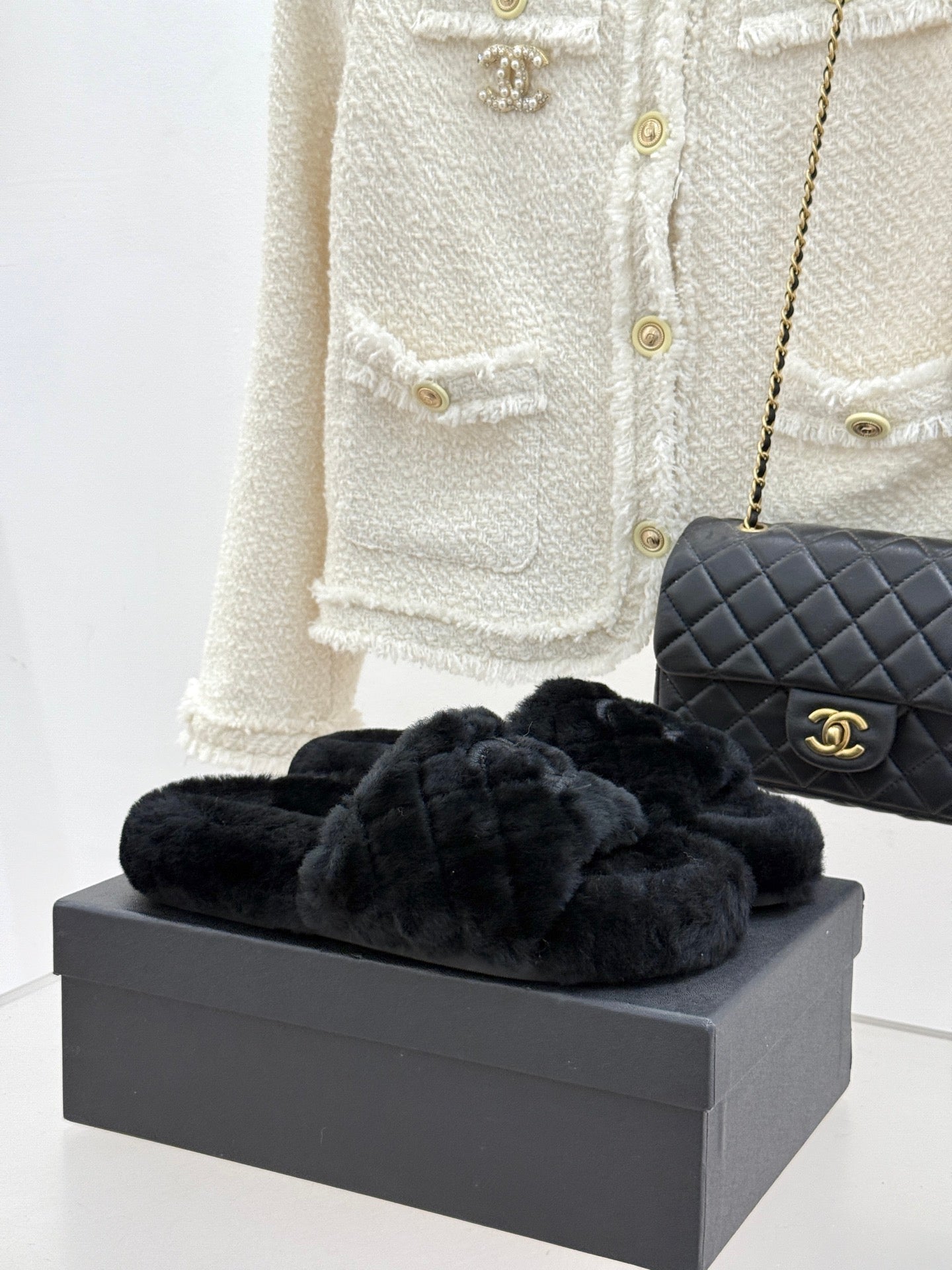 Dark faux-fur Chanel slides with quilted strap and CC logo, on display box