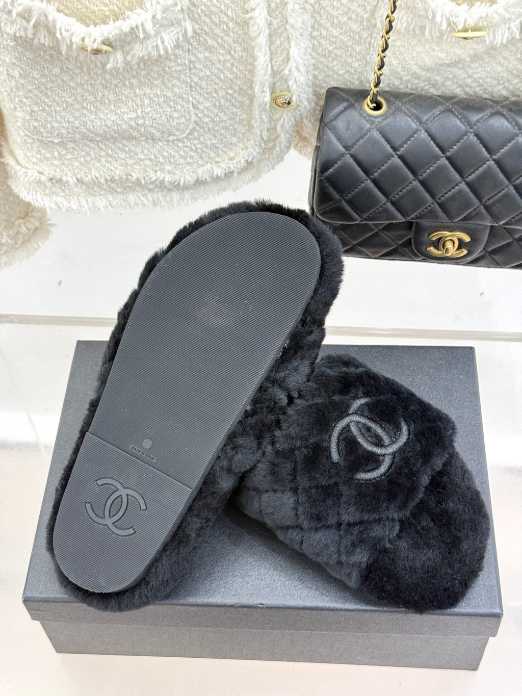 Dark faux-fur Chanel slide with flat sole showing CC logo, on gray box