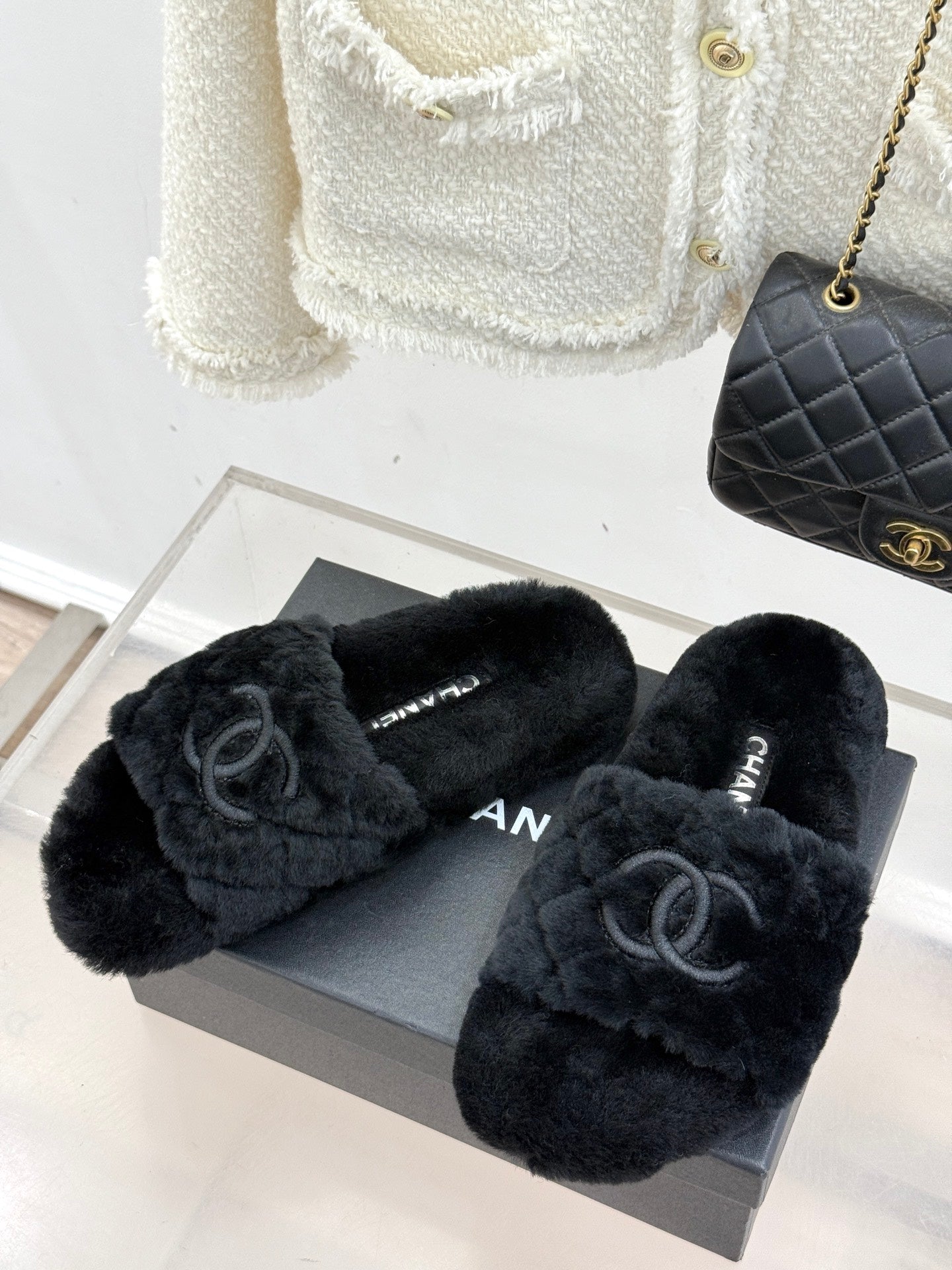 Pair of dark faux-fur Chanel slides with front CC emblems, on gray shoe box