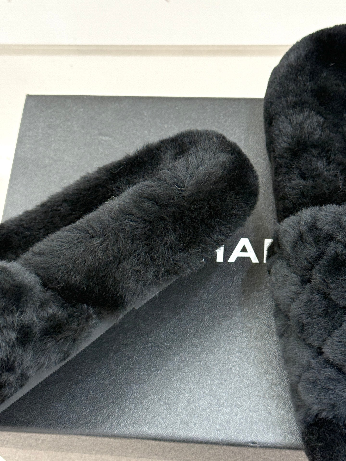 Close-up of dark faux-fur Chanel slide strap on gray box