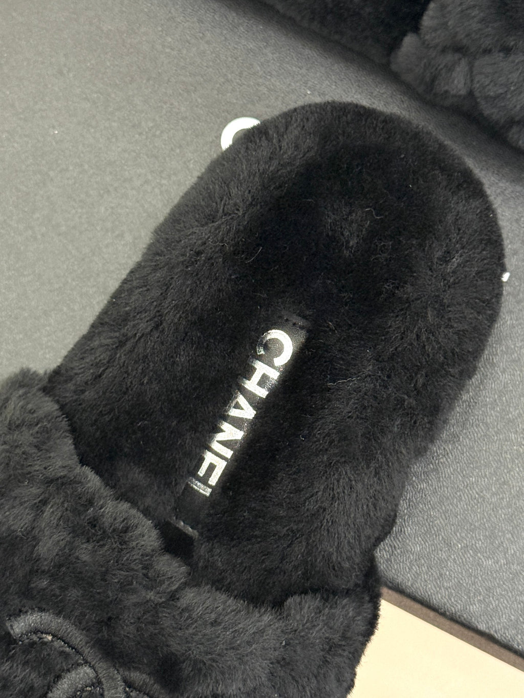 Close-up of dark faux-fur Chanel slide sole with embossed text