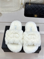 White faux-fur open mules with Chanel logo, displayed on black box