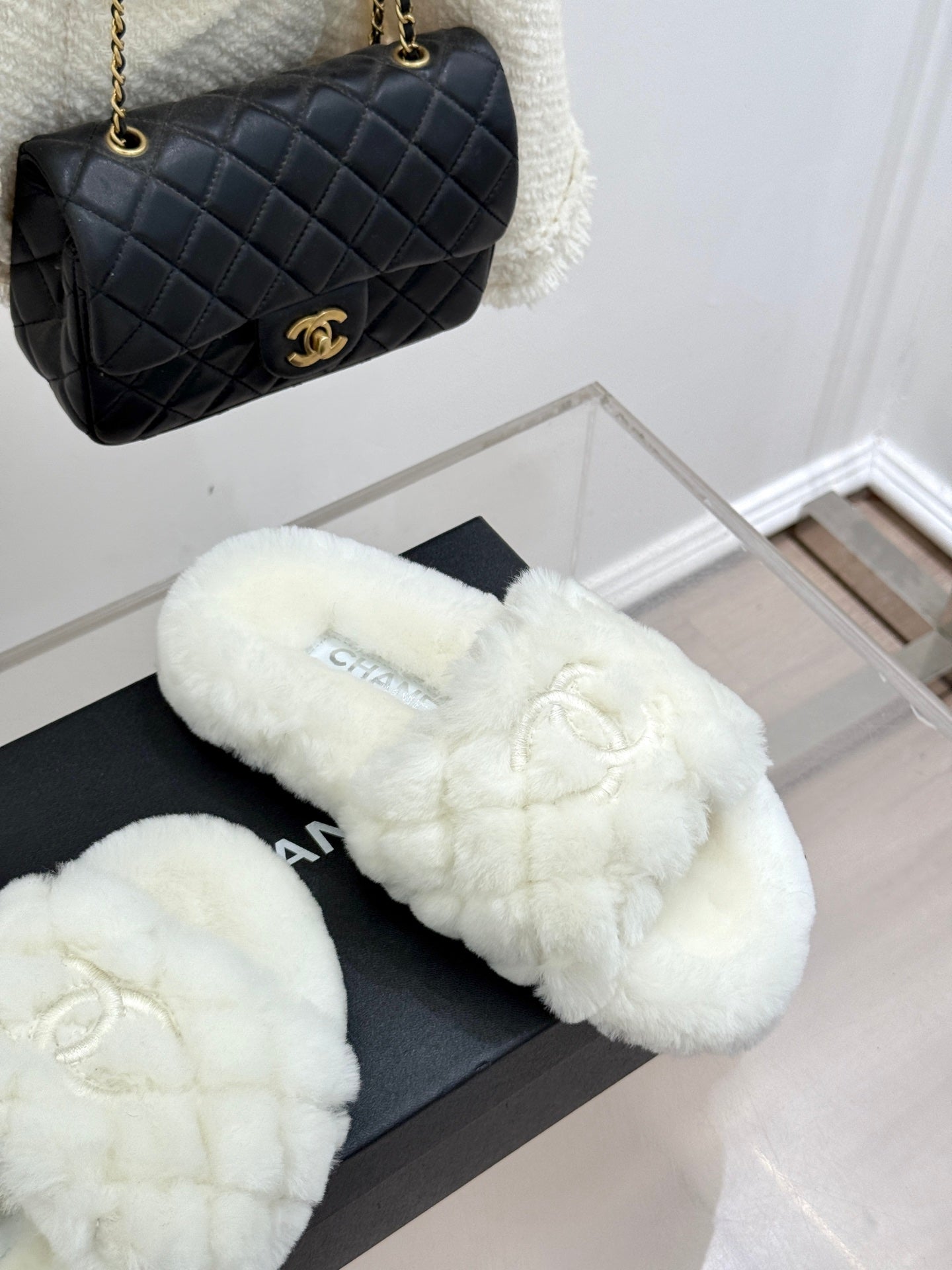 White faux-fur slide mules with Chanel logo on black box