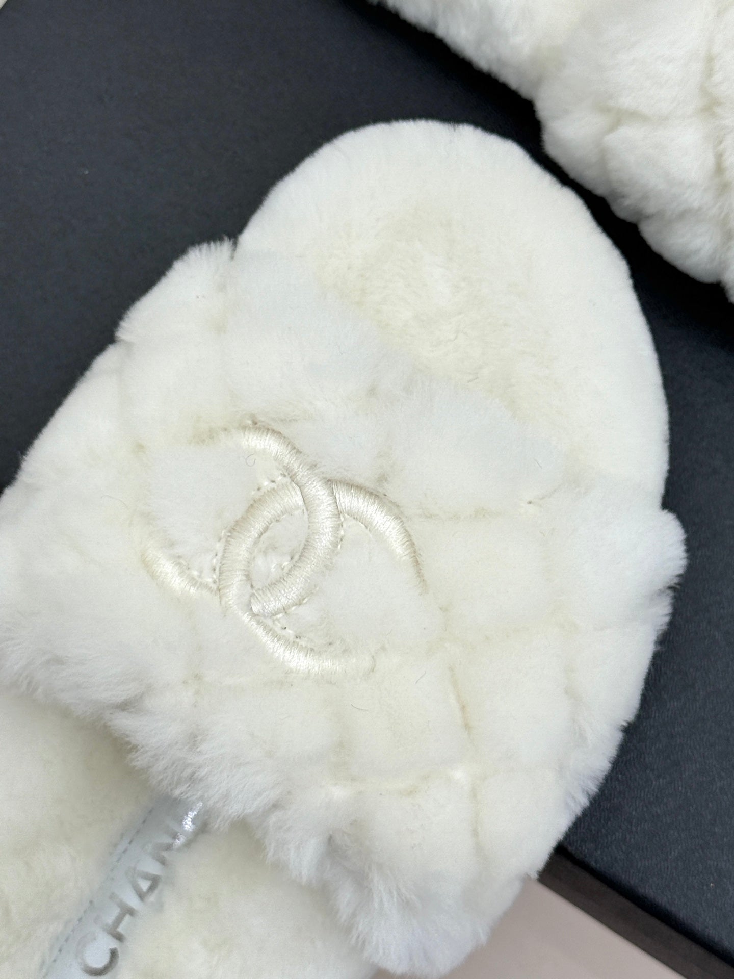 Close-up: white faux-fur round-toe mule with Chanel logo stitch