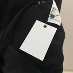 Black sweatshirt with hanging white brand tag on the collar