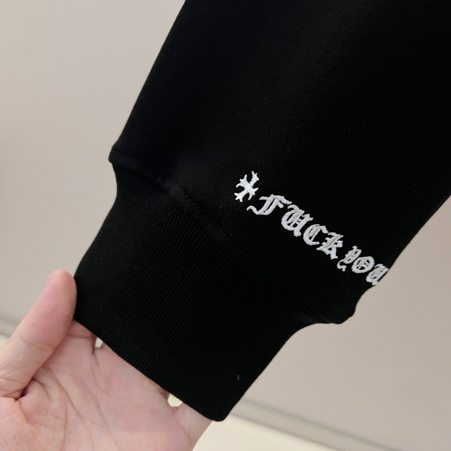 Black sweatshirt cuff with embroidered logo text