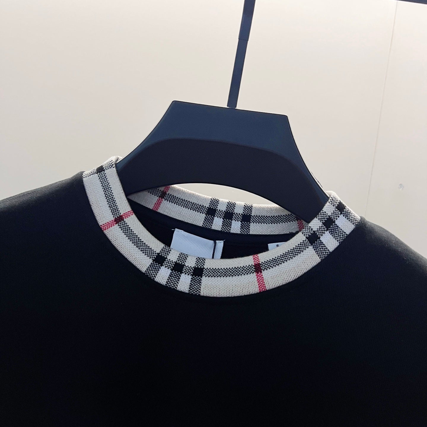 Navy sweatshirt neckline with Nova Check ribbed collar featuring black, white, and red stripes