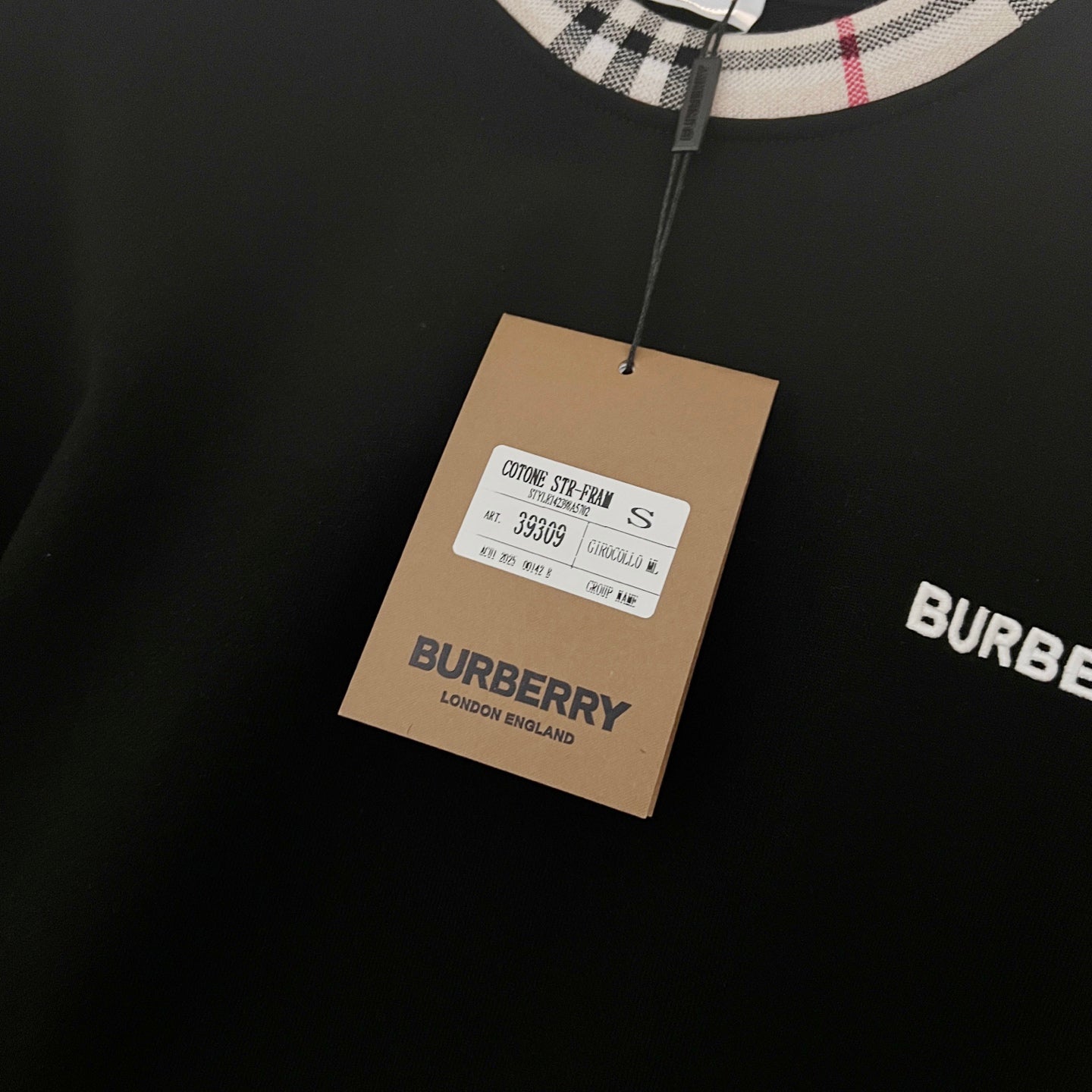 Navy sweatshirt with hanging fabric tag and Burberry label detail near the collar