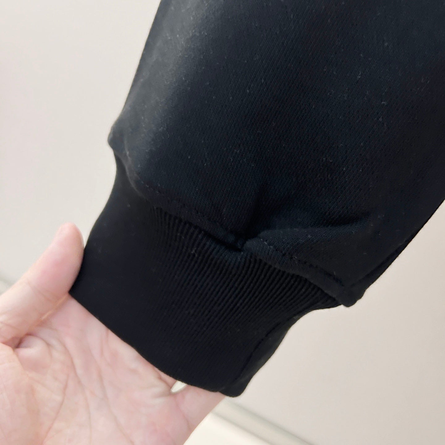 Navy sweatshirt sleeve cuff and hem with ribbed knit texture, held in a hand