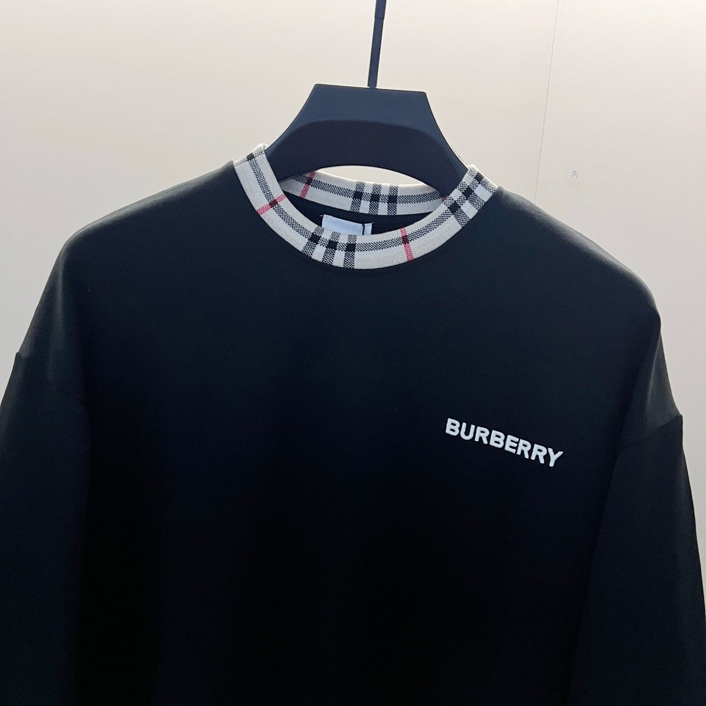 Navy crewneck sweatshirt close-up with Nova Check ribbed collar and Burberry logo on chest