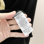 Kids long-sleeve sweatshirt care label on dark navy fabric, tag held in hand