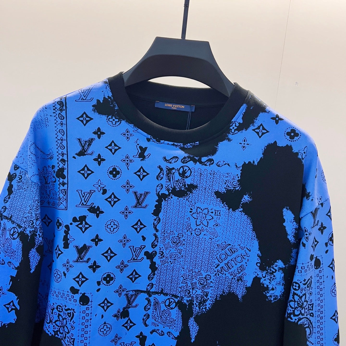 Long-sleeve sweatshirt with blue-and-black patchwork-like logo print and ribbed collar