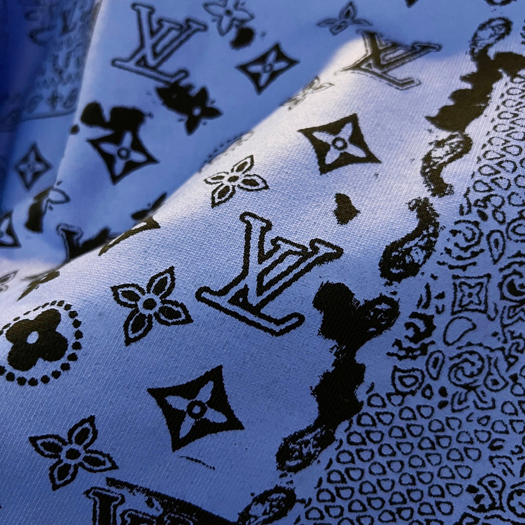Sweatshirt fabric close-up showing blue ground with black icon and monogram motifs