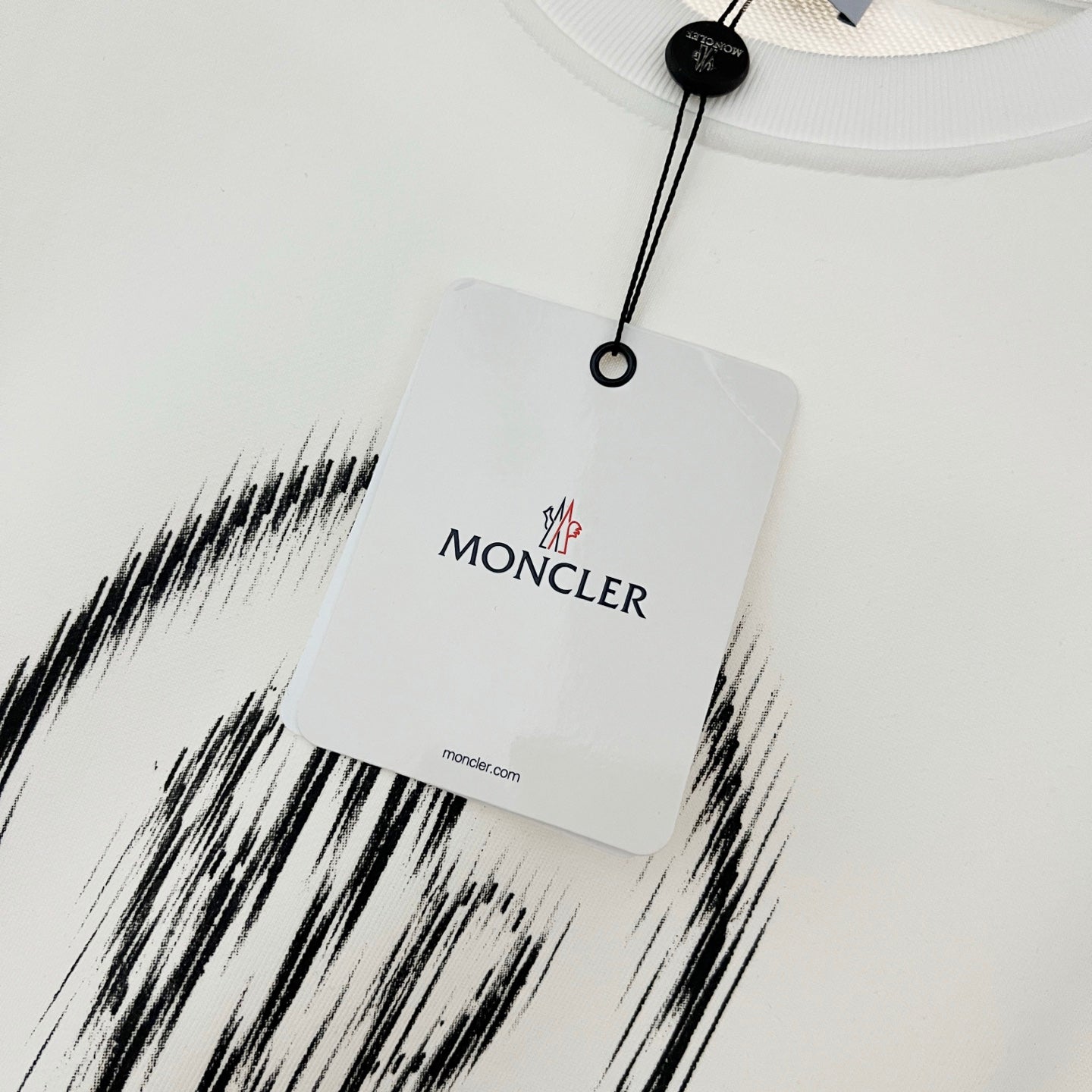 White sweatshirt neckline with hanging tag and MONCLER branding