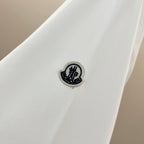 White sweatshirt sleeve with small round Moncler logo patch