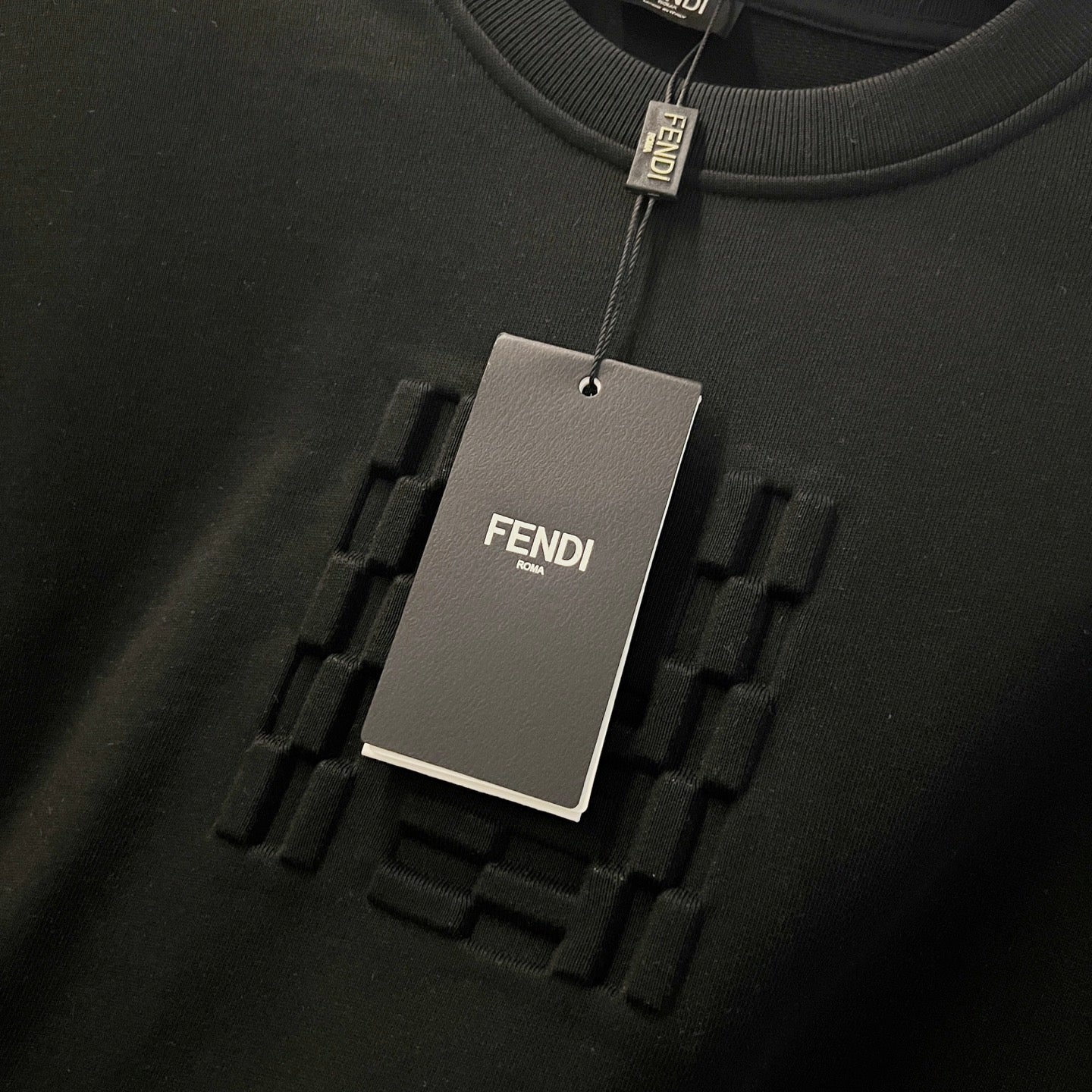 Black sweatshirt hang tag and raised Fendi logo detail on fabric