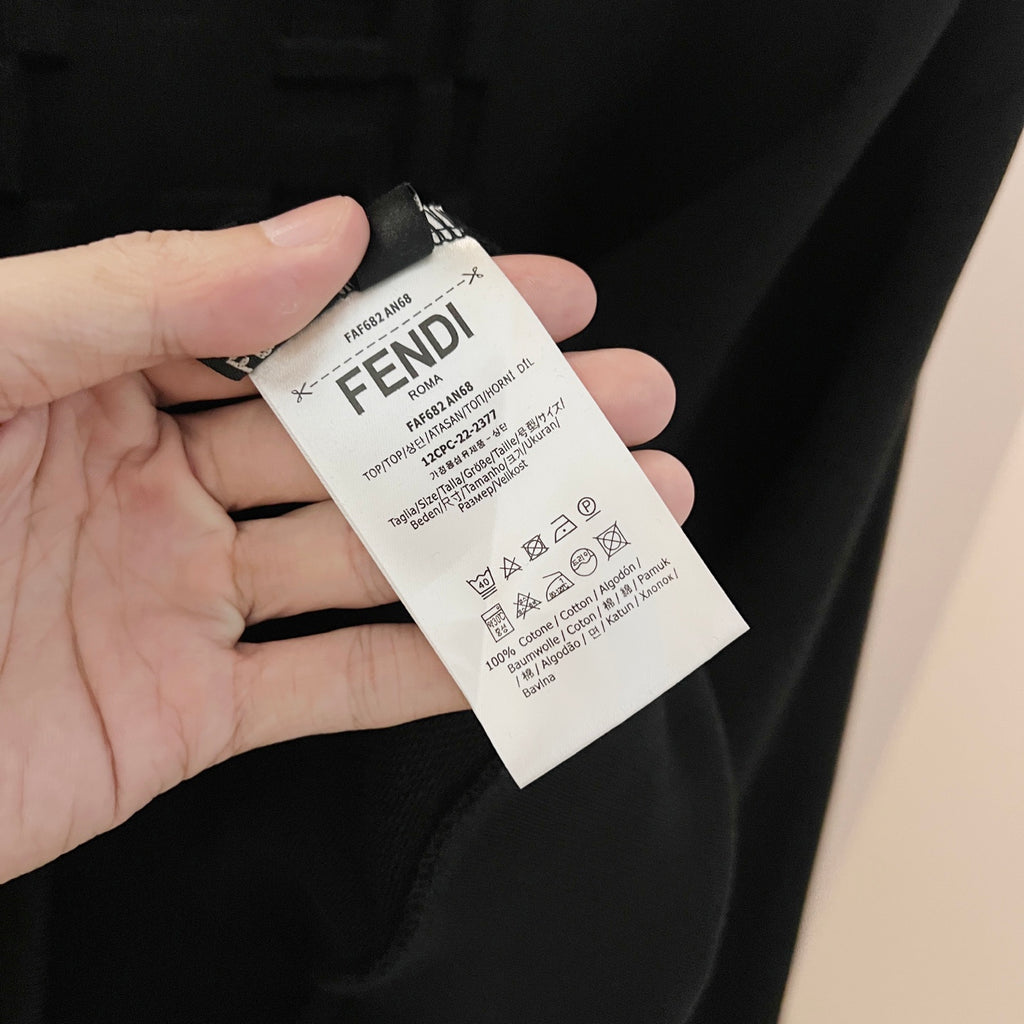 Black sweatshirt with Fendi care tag held in hand