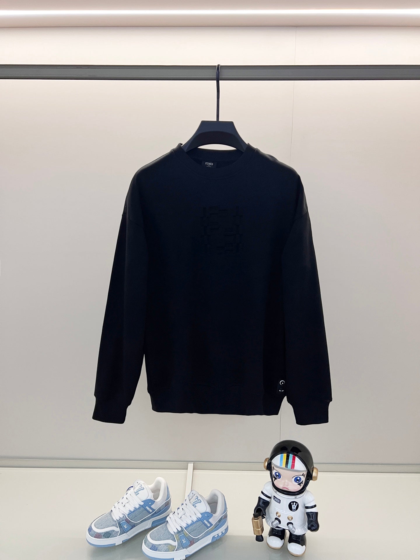 Black crewneck sweatshirt with ribbed cuffs and hem on a hanger