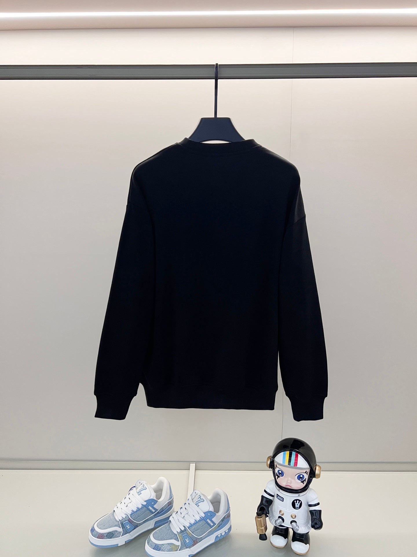 Black crewneck sweatshirt back view on a hanger
