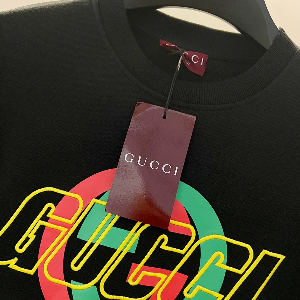 Black sweatshirt with large multicolor GUCCI graphic logo, hanging brand tag.