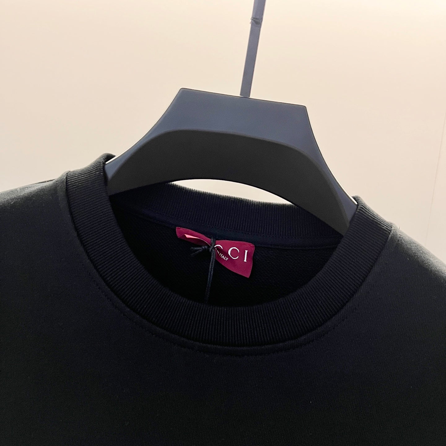 Black crewneck sweatshirt neckline with ribbed collar and inner label.