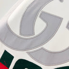 Close-up of embroidered Gucci logo on white hoodie with grey lettering