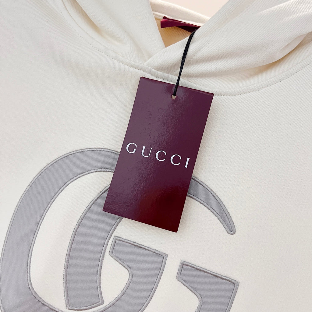 White hoodie hood tag reading Gucci, attached near neckline