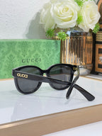 Gucci sunglasses with black frames and tinted lenses, logo on front