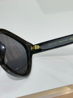 Gucci sunglasses temple close-up with gold logo detail and dark frame