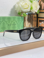 Gucci sunglasses with dark frames and large square lenses, logo on temples
