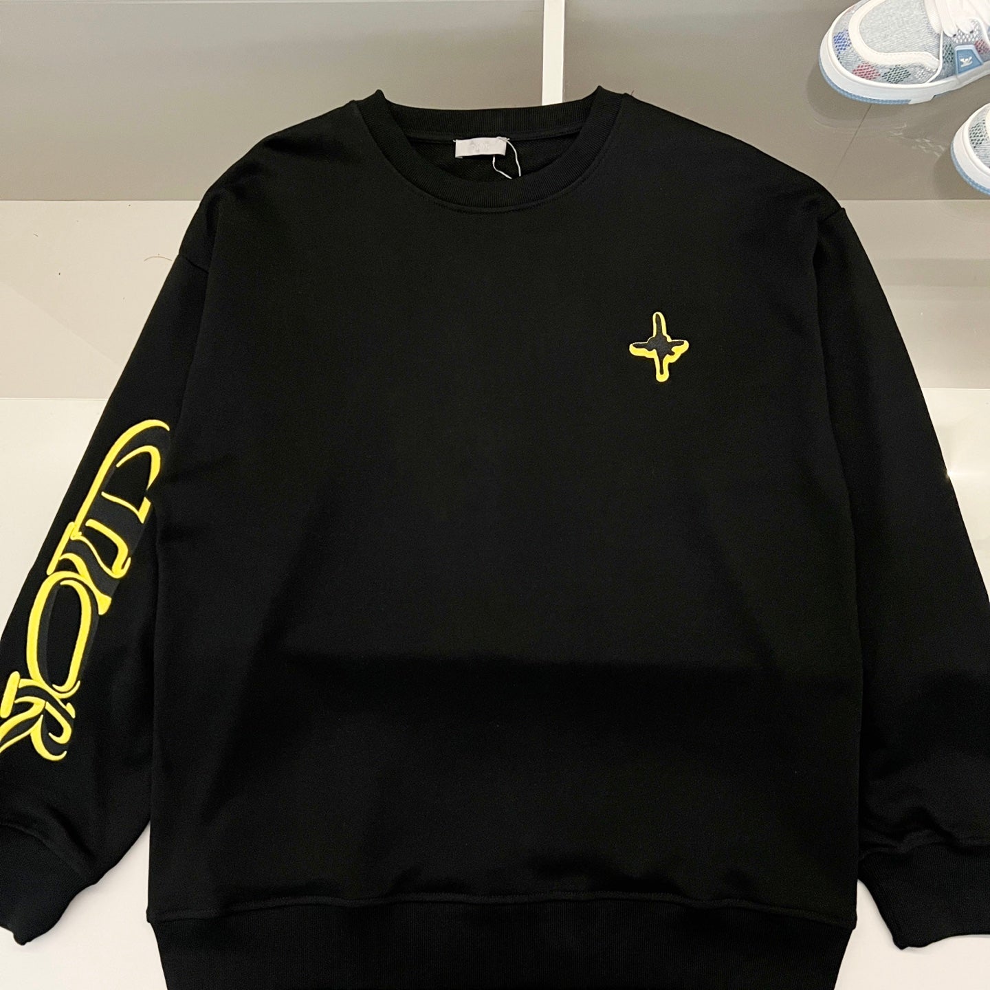 Black long-sleeve crewneck shirt with neon yellow cross detail