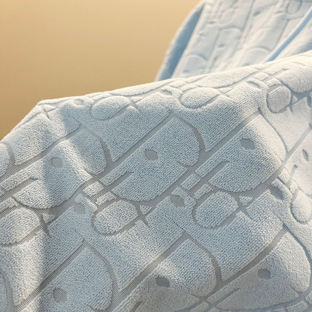 Light blue hoodie fabric with raised allover logo pattern texture