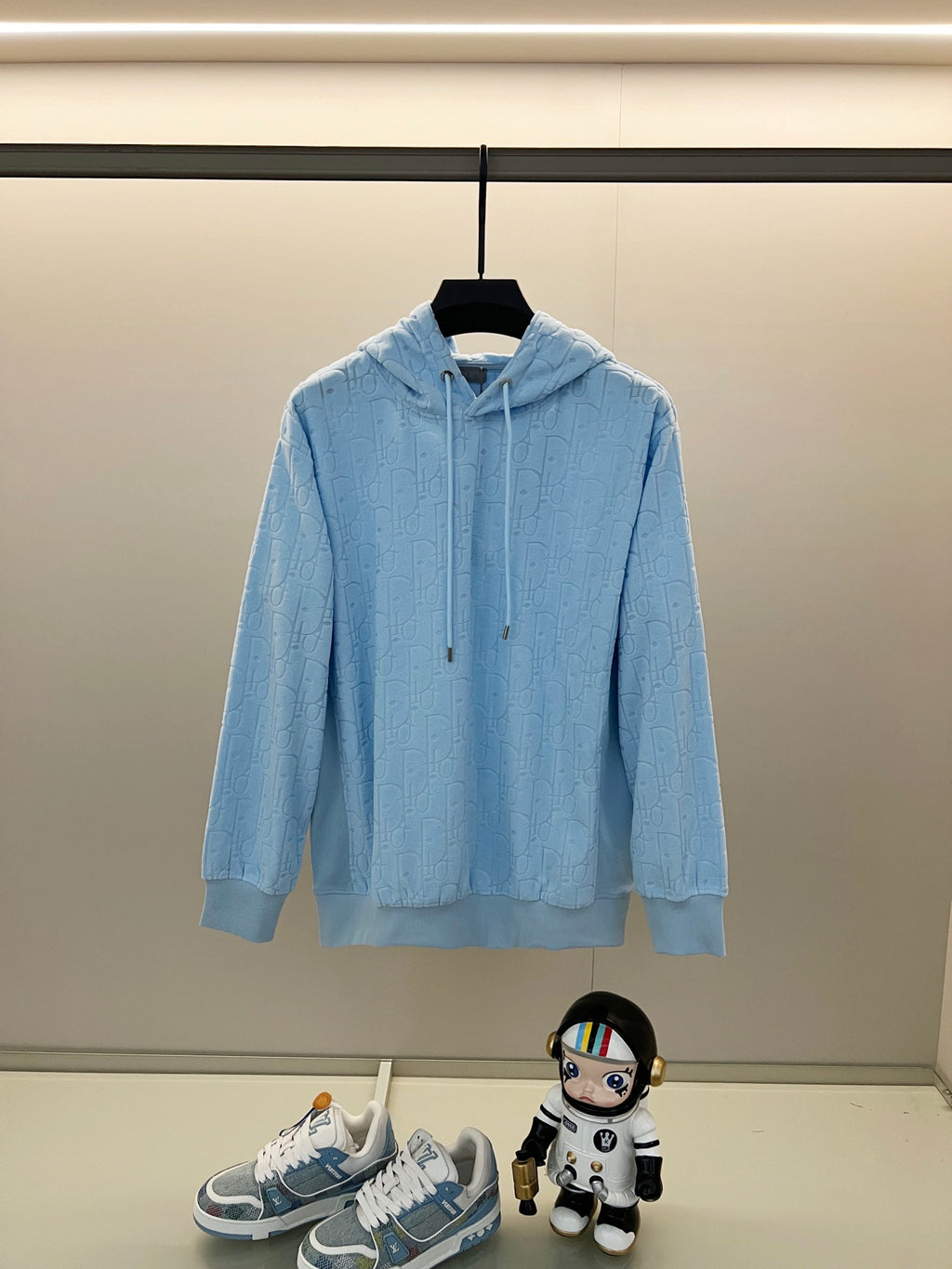 Light blue hoodie with allover logo pattern, front kangaroo pocket, and drawstring hood