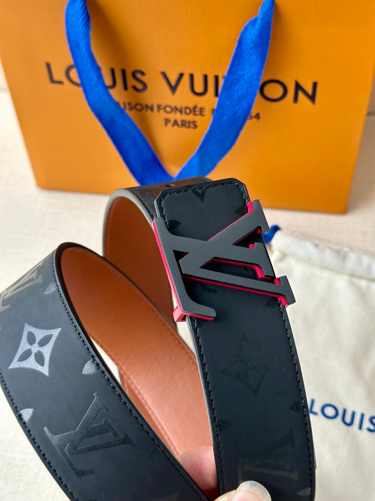 Louis Vuitton belt buckle detail with dark monogram strap and brown leather back