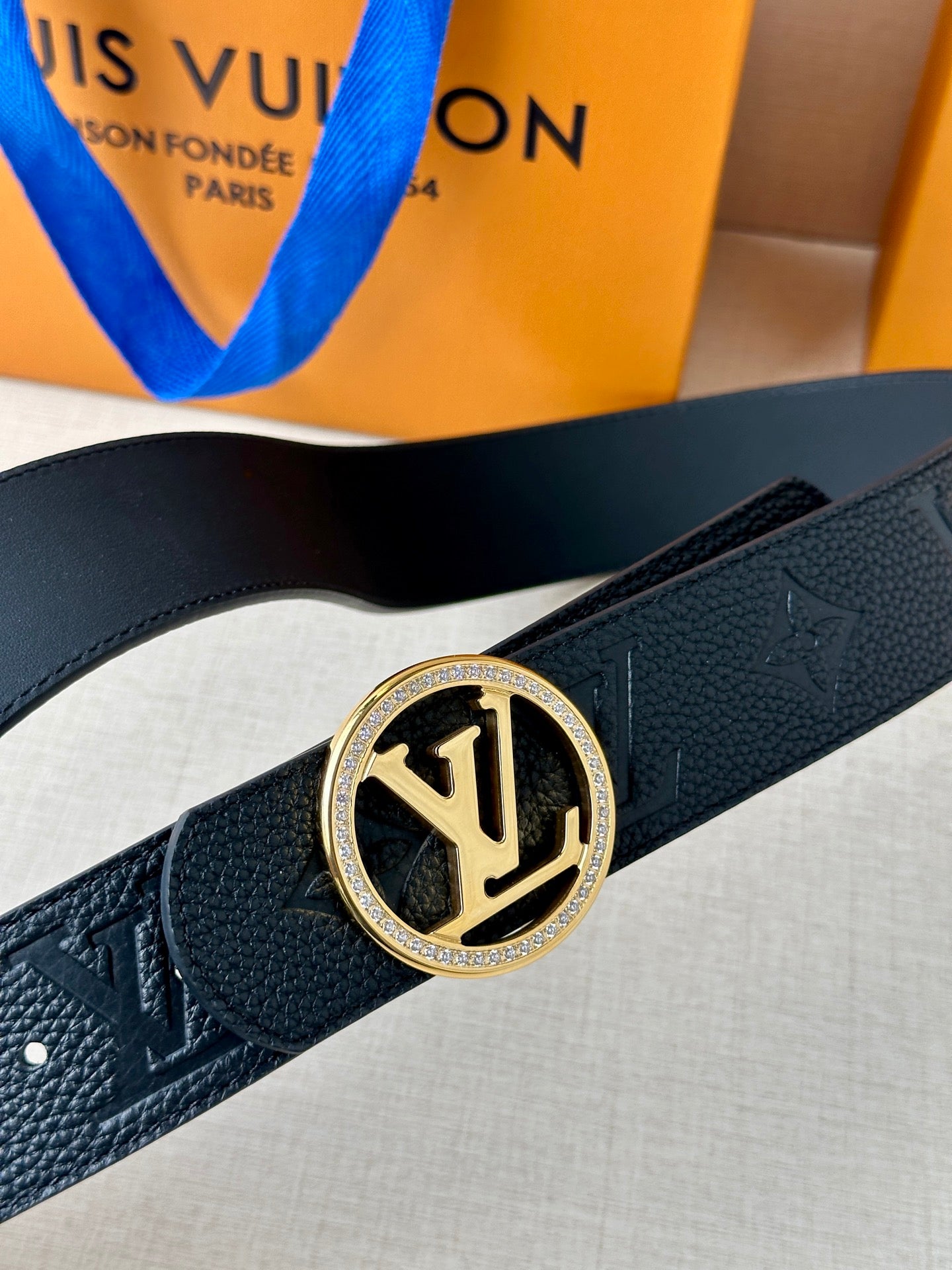 Louis Vuitton belt buckle on dark leather strap with monogram emboss and gold rim