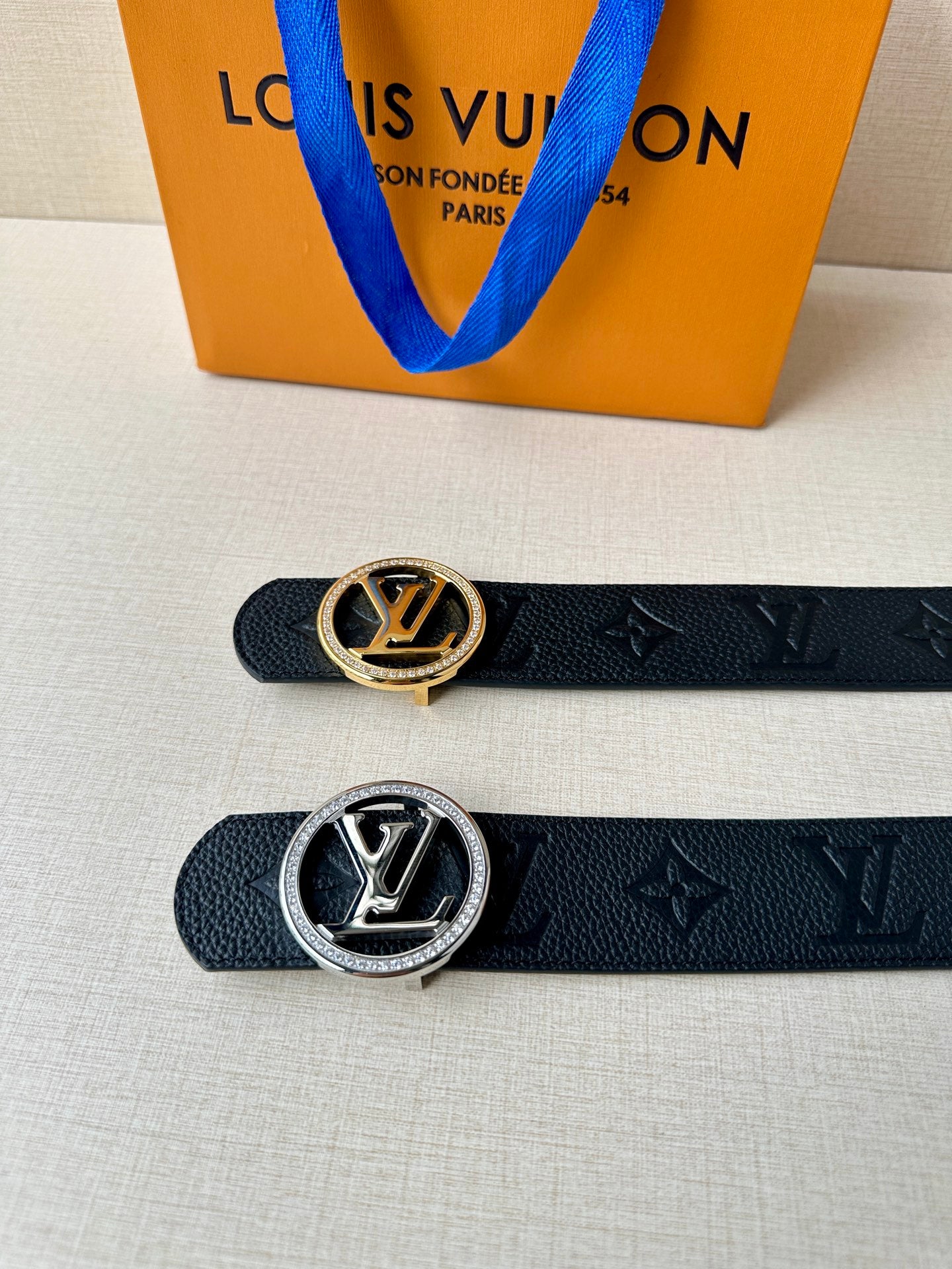 Louis Vuitton belts with gold and silver logo buckles on dark embossed monogram straps