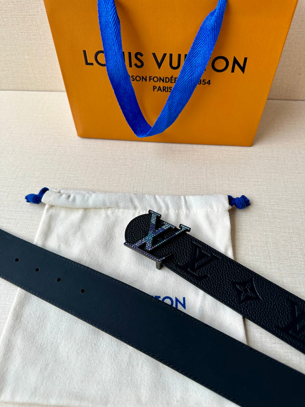 Louis Vuitton belt laid on pouch: dark leather strap with LV buckle and monogram