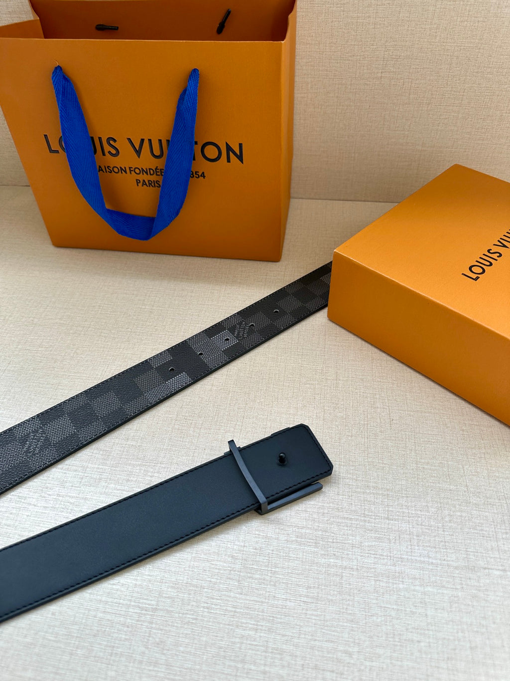 Dark gray check belt with silver buckle, plus dark leather strap and pin holes