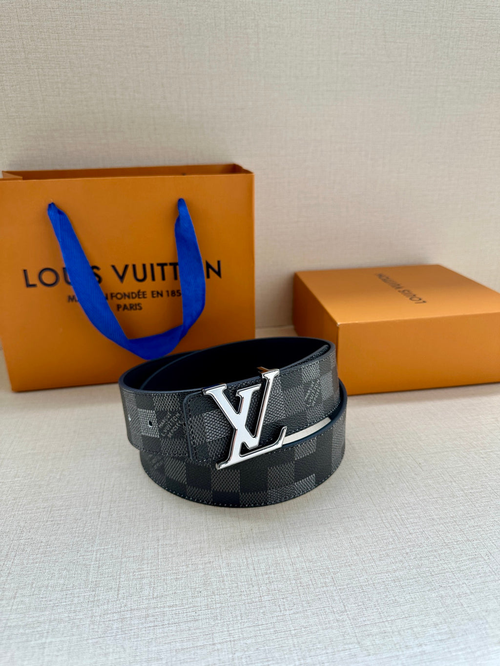 Dark gray check belt with oversized silver LV buckle and adjustable holes